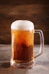 Glass mug of light beer on wooden table, close up