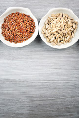 Flax and sunflower seeds in bowl on wooden table
