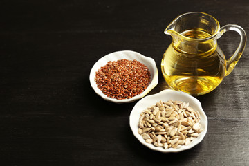 Flax and sunflower seeds with oil on wooden table