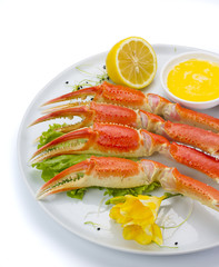 Boiled crab claws with sauce and lemon on a plate over white background