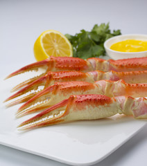 Boiled crab claws with sauce and lemon on a plate over white background