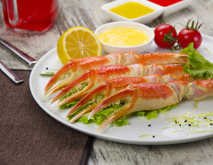 Boiled crab claws with sauce , lemon and cherry tomatoe with tasty drink over wooden background