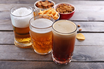 Various types of beer and snacks on wooden table