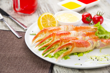 Boiled crab claws with sauce , lemon and cherry tomatoe with tasty drink over wooden background