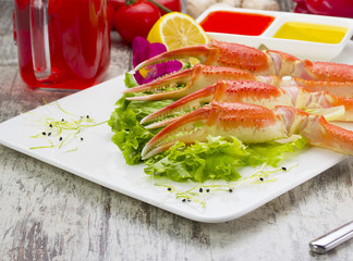 Boiled crab claws with sauce , lemon and cherry tomatoe with tasty drink over wooden background