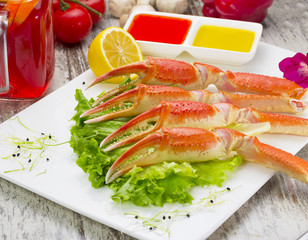 Boiled crab claws with sauce , lemon and cherry tomatoe with tasty drink over wooden background
