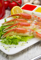 Boiled crab claws with sauce , lemon and cherry tomatoe with tasty drink over wooden background