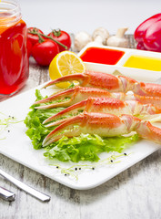 Boiled crab claws with sauce , lemon and cherry tomatoe with tasty drink over wooden background