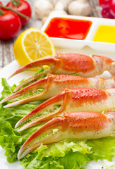 Boiled crab claws with sauce , lemon and cherry tomatoe over wooden background