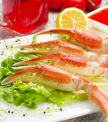 Boiled crab claws with sauce , lemon and cherry tomatoe with tasty drink over wooden background