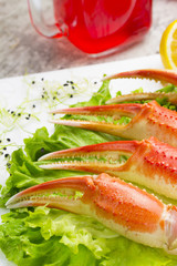 Boiled crab claws with sauce , lemon and cherry tomatoe with tasty drink over wooden background