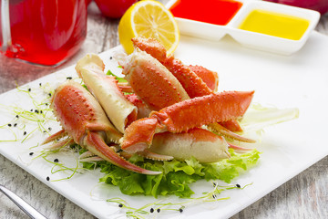 Boiled crab claws with sauce , lemon and cherry tomatoe with tasty drink over wooden background