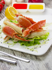 Boiled crab claws with sauce , lemon and cherry tomatoe over wooden background