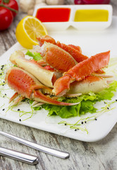 Boiled crab claws with sauce , lemon and cherry tomatoe over wooden background