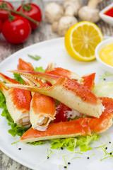Boiled crab claws with sauce , lemon and cherry tomatoe over wooden background