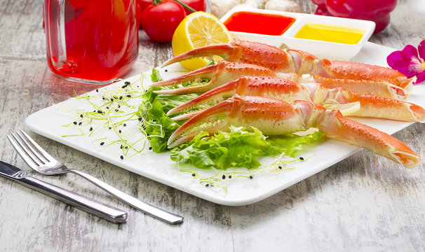 Boiled crab claws with sauce , lemon and cherry tomatoe with tasty drink over wooden background