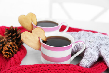 Heart shape cookie on cup of coffee with red knitted scarf closeup