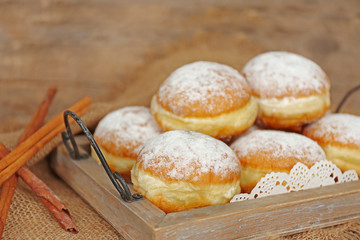 Delicious sugary donuts in wooden tray closeup