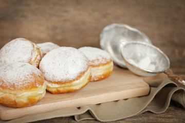 Delicious sugary donuts on wooden cutting board closeup