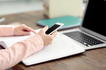 Woman working with notebook and using devices at the table in office