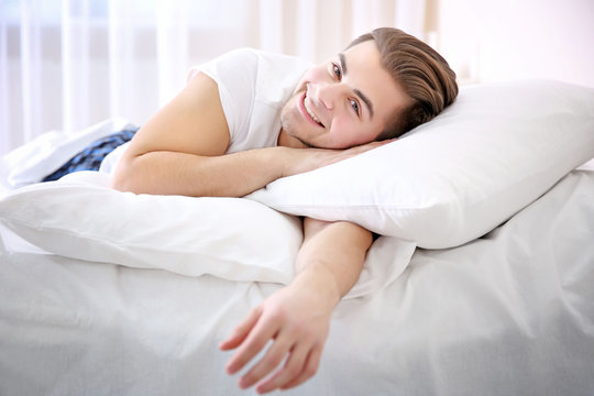 Young smiling man lying in bed at home