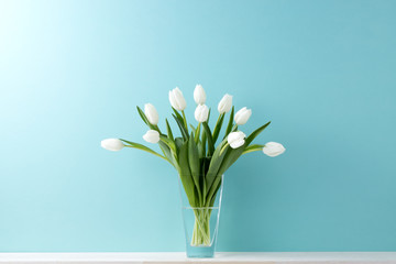 青い背景と棚と花瓶と白いチューリップ