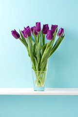 青い背景と棚と花瓶と紫色のチューリップ