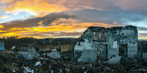The remains of destroyed houses at sunset