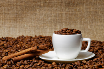 Coffee cup full of coffee beans and cinnamon sticks