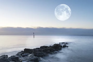 Acrylic prints Coast Stunning sunrise landscape over rocks in sea with super moon