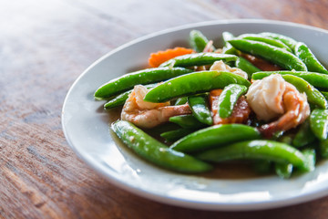 Shrimp stir and fried and green peas on white plate with selective focus