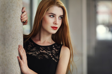 Outdoor lifestyle portrait of pretty young girl wearing in black dress on urban background.