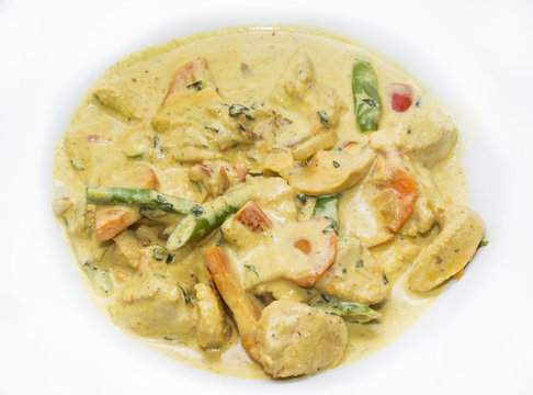 chicken curry with vegetables on a white plate in a restaurant