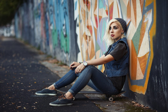 Outdoor lifestyle portrait of pretty young girl, wearing in hipster swag grunge style on urban background with graffiti. Retro vintage toned image, film simulation.