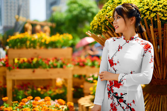 Asian Beauty Woman. Beautiful Happy Vietnamese Girl Wearing National Traditional White Ao Dai Dress ( Clothing, Costume), Standing In Flower Garden, Ho Chi Minh City, Vietnam. Culture Of Asia