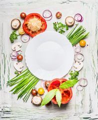 Various vegetables and seasoning cooking  ingredients around blank plate on light  rustic wooden...