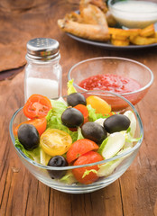 salad bowl in front of a plate of chicken wings