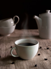 hot a cup of coffee with soft smoke around beans selective focus on vintage background.