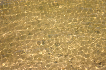 Fototapeta na wymiar sandy bottom through the water surface in shallow water