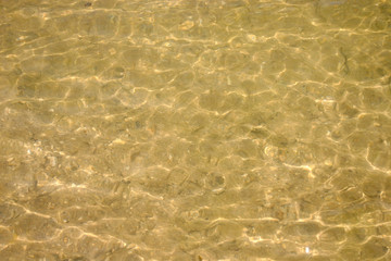 sandy bottom through the water surface in shallow water