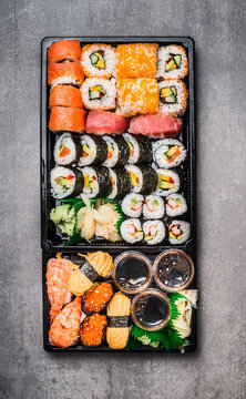 Various Sushi selection in black packaging tray on gray stone background, top view. Top view composing.  Japanese and Asian food.