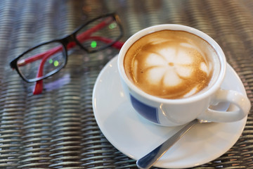 hot latte coffee, white coffee cup on table with eyeglasses