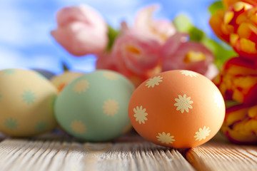 Colorful Easter eggs and spring flowers on sky background