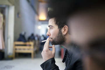 Handsome stylish young man smoking outside