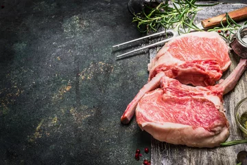 Fototapete Fleish Raw gourmet pork cutlet for grill, barbecue or cooking with herbs ,spices and meat fork on dark rustic background. Porco Iberico French Racks. Meat food. Pork rib chop with bone.