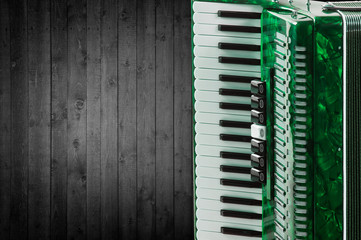 Part green accordion on wooden grey background. Write text