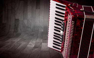 Part red accordion on wooden grey background. Write text