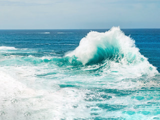 Turquoise ocean wave breaking rough seas, with water foam and blue sea water