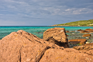 Red rocks and turquoise water at beach in San Pietro island, Sardinia, Italy