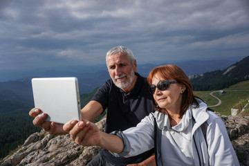 Elderly couple using a tablet on top of a mountain - 104642744